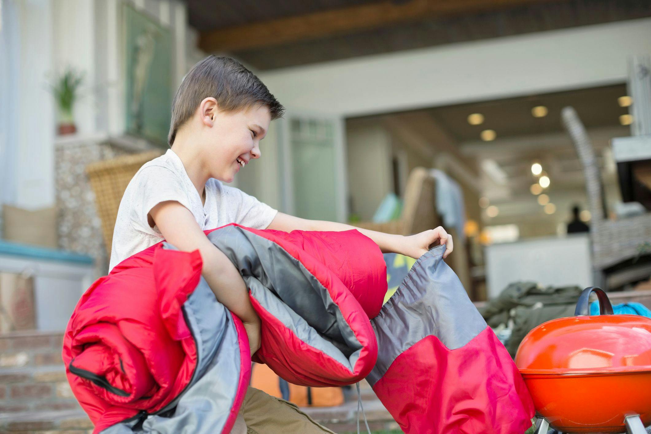 boy-packing-his-sleeping-bag-for-camping-trip
